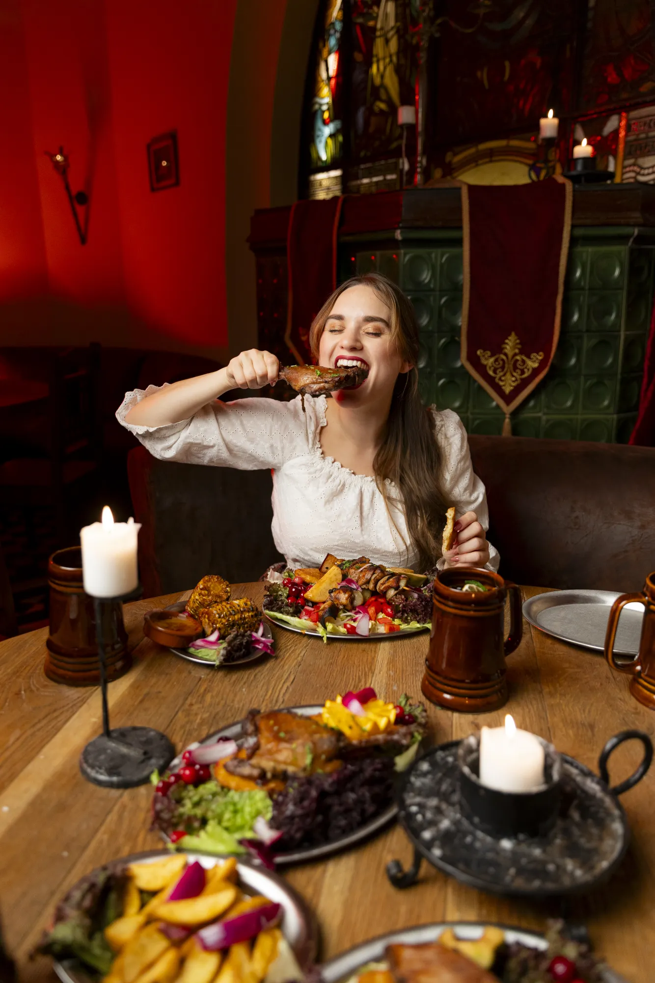 Beautiful woman taking a bite of food over a table full of food.